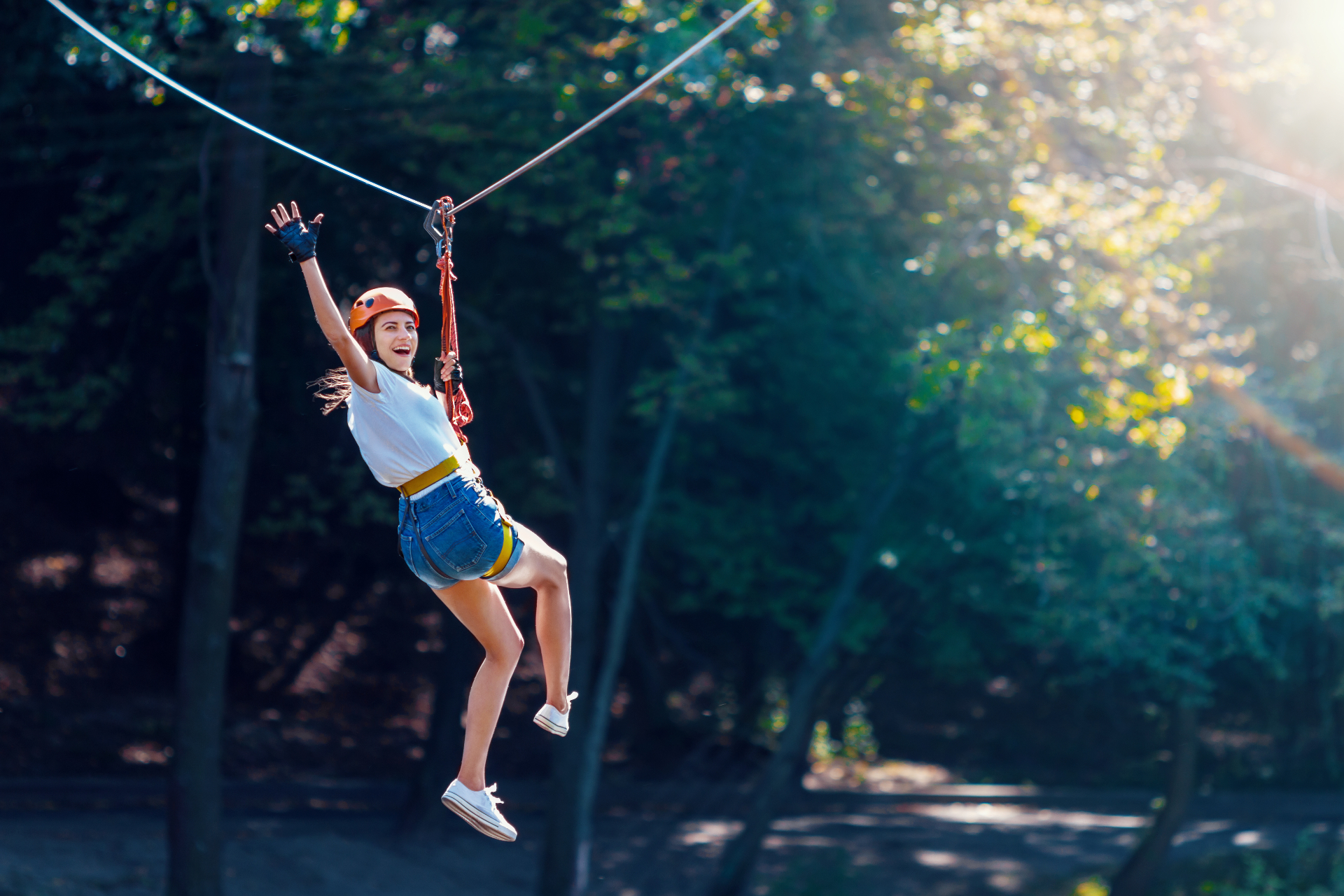 Une femme survolant la forêt en tyrolienne, pleine d'énergie et de joie
